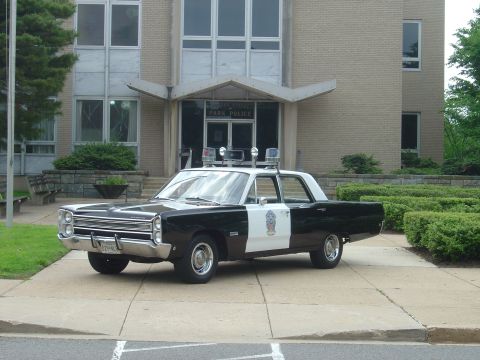 2001 Ford Crown Victoria - A vintage black and white police car is parked on a sidewalk in front of a building with 'Park Police' signage above the entrance.