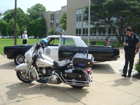 2001 Ford Crown Victoria - A police motorcycle and a vintage police car are displayed side-by-side.