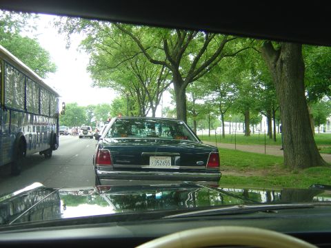 2001 Ford Crown Victoria - A dark 2001 Ford Crown Victoria is seen from behind in traffic, with a bus to its left.