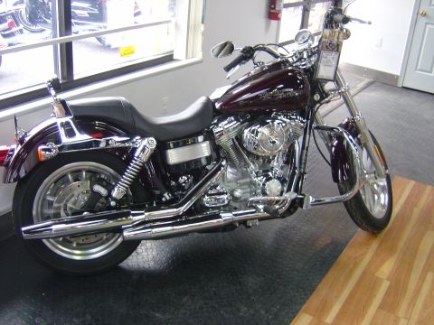 2001 Ford Crown Victoria - Maroon Harley-Davidson motorcycle with chrome accents is displayed indoors on a black floor.
