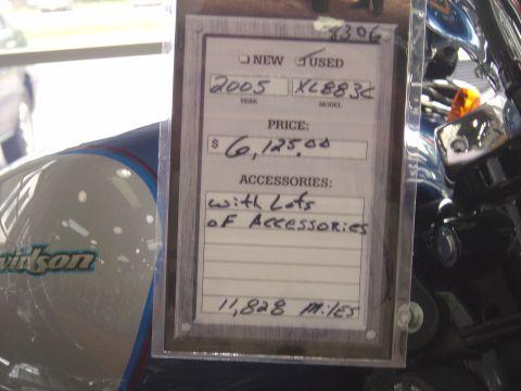 2001 Ford Crown Victoria - A motorcycle's fuel tank is visible next to a price tag detailing its year, price, and mileage.