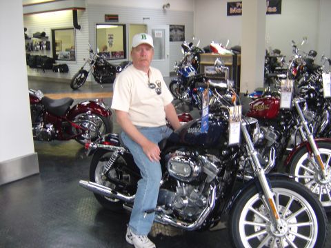 2001 Ford Crown Victoria - A man sits on a motorcycle inside a dealership with several other motorcycles visible.