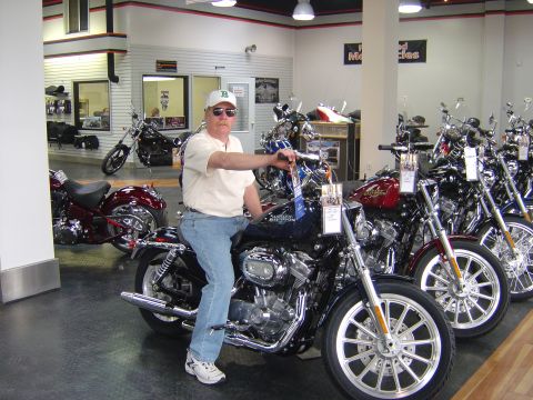 2001 Ford Crown Victoria - A man sits on a dark blue Harley-Davidson motorcycle inside a dealership, with other motorcycles visible in the background.