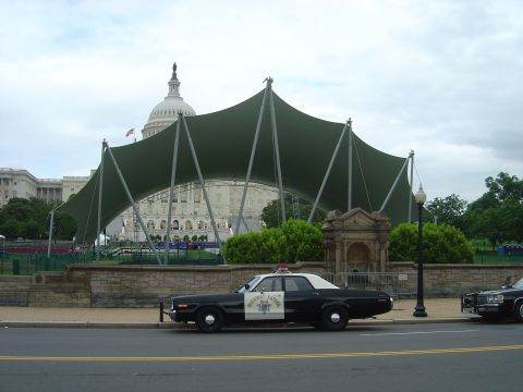 2001 Ford Crown Victoria - A vintage police car is parked on the street, with the US Capitol building and a large tent structure visible behind it.