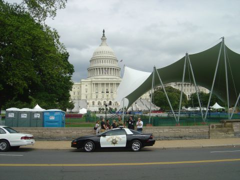 2001 Ford Crown Victoria - A police car and a white sedan are parked on a street in front of the US Capitol building.