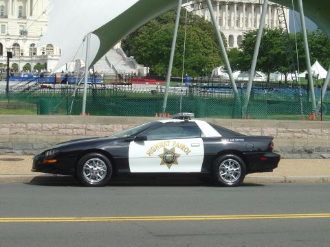 2001 Ford Crown Victoria - Side view of a police car with 'HIGHWAY PATROL' markings, parked near a building.