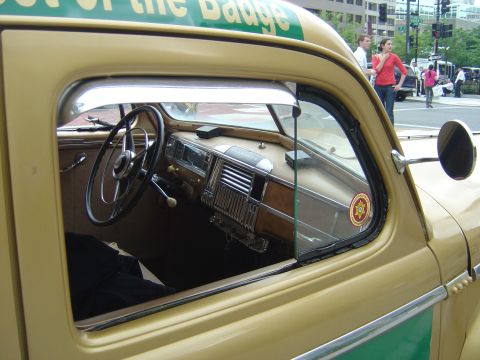 2001 Ford Crown Victoria - The interior of a classic police car is visible through the open window, with a badge on the glass.