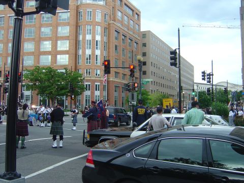2001 Ford Crown Victoria - A street scene unfolds with bagpipers, police, and onlookers gathered in an urban environment.