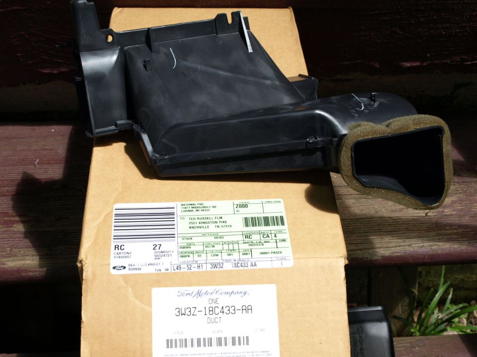 Black plastic air duct with foam seal on a cardboard box with shipping labels