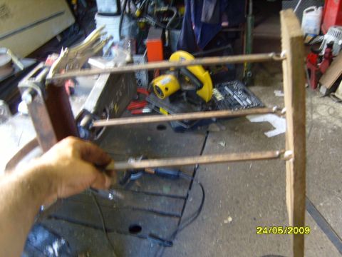 1989 Ford Bronco - A wooden frame with copper pipes is being held by a hand, with tools and equipment in the background.