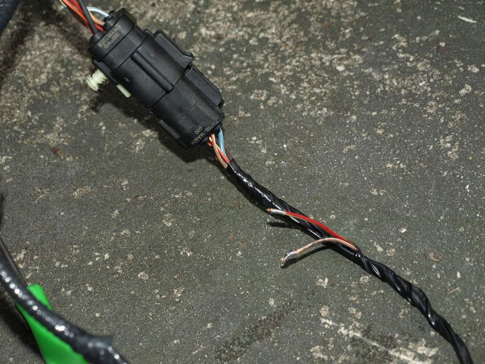 close-up of a black electrical connector with wires attached, some taped and frayed