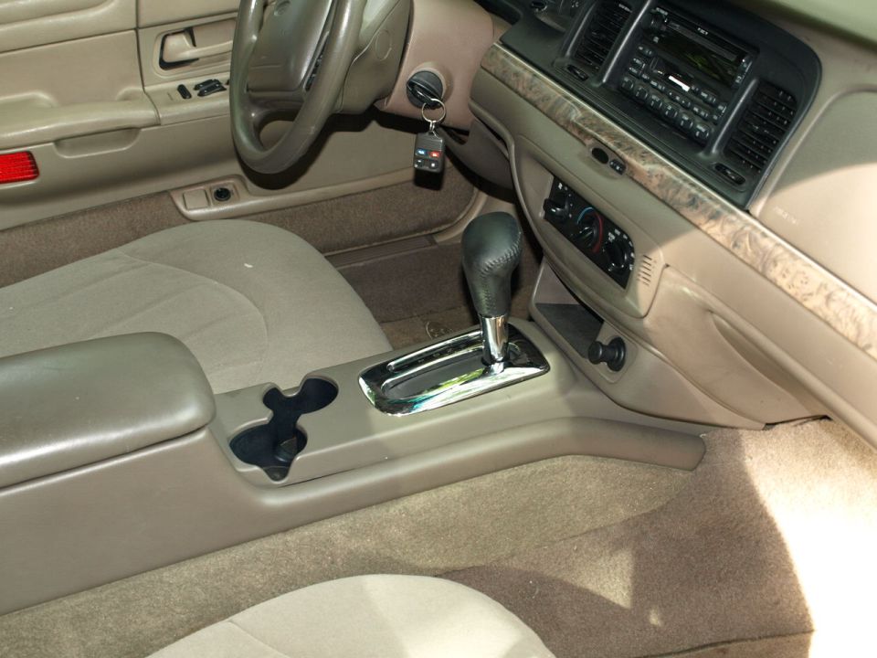 Car interior with tan upholstery, automatic transmission shifter, and dashboard. A Supermotors.net watermark is visible