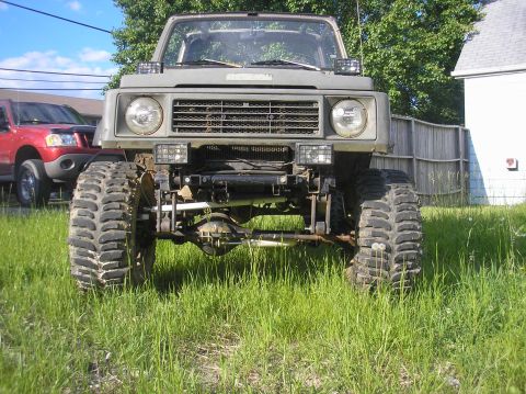 1987 Suzuki Samurai - Modified 1987 Suzuki Samurai parked in grass, showing its lifted suspension and large tires.