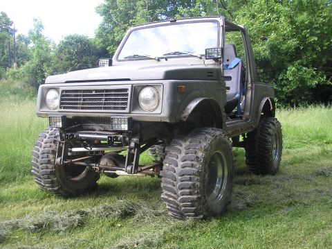 1987 Suzuki Samurai - This heavily modified SUV sits high on its suspension with aggressive off-road tires, ready for rough terrain.