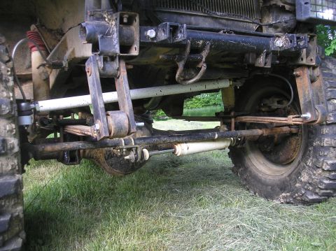 1987 Suzuki Samurai - The front suspension of a 1987 Suzuki Samurai is visible, showing its leaf spring setup and off-road modifications.