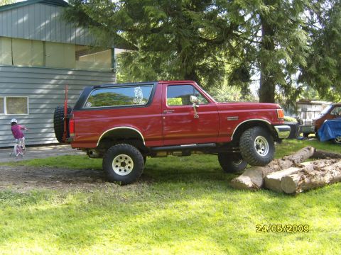 1989 Ford Bronco - This red 1989 Ford Bronco is shown in a three-quarter front view, with its spare tire mounted on the rear.