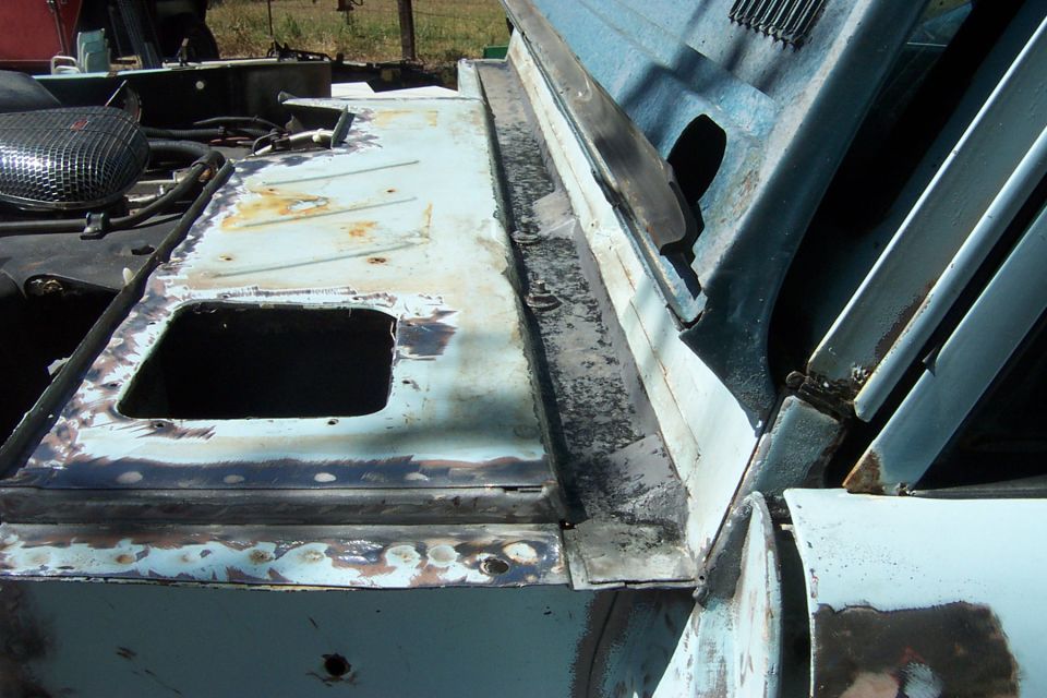 Light blue car body panel with rust and primer, showing a square cutout and metalwork