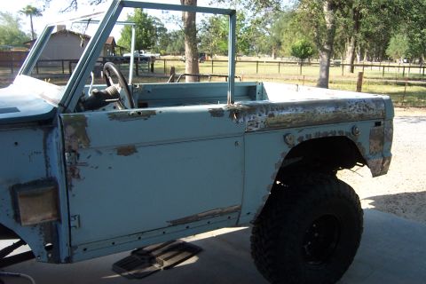 1976 Ford Bronco - This 1976 Ford Bronco body shows signs of rust and primer beneath its light blue paint, viewed from the front three-quarter angle.
