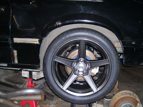 1990 Ford Mustang - Close-up of a car's wheel and fender area, showing aftermarket wheels and brake components.