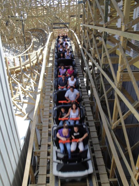 1993 Ford Taurus - A roller coaster train full of passengers navigates a wooden track, viewed from above.