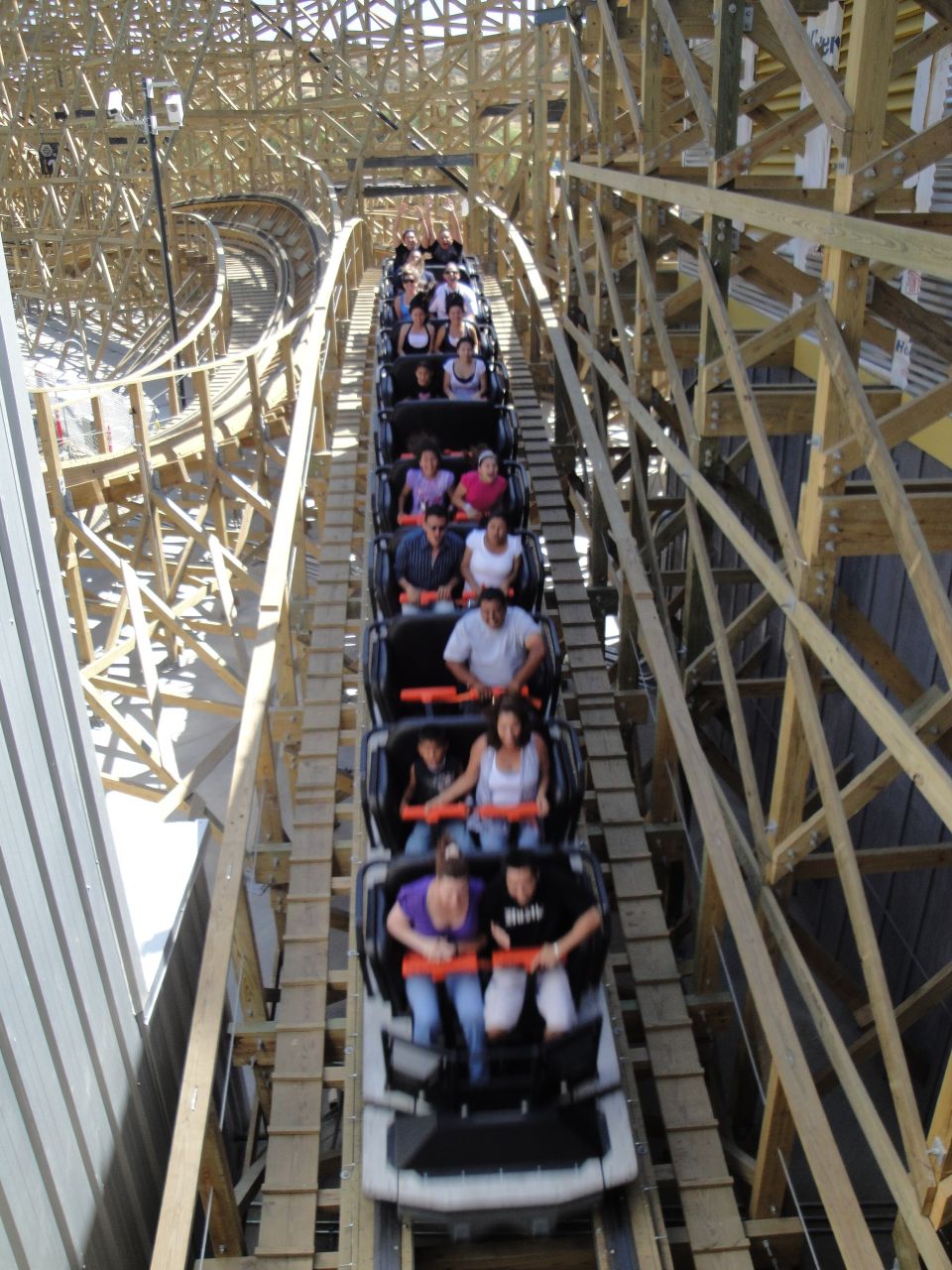 Roller coaster train with passengers descending a wooden track