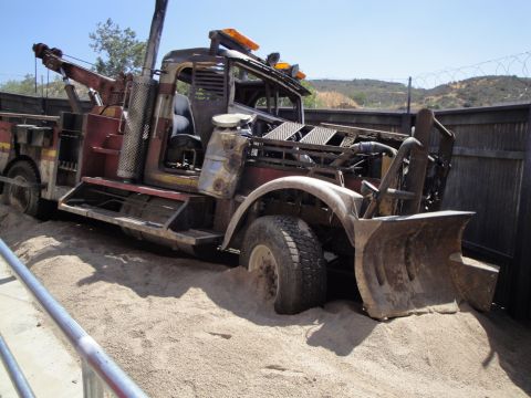 1993 Ford Taurus - This heavily modified tow truck, equipped with a plow, appears stuck in a sandy area.