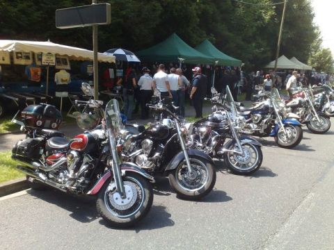 1991 Ford Crown Victoria - A row of cruiser motorcycles are parked on pavement, with tents and people visible in the background.