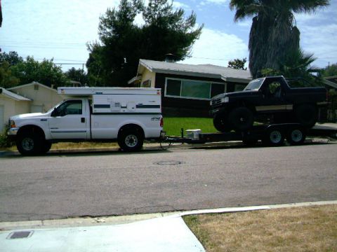 2000 Ford F-250 - White 1997 Ford F-250 with camper shell tows trailer carrying a black Bronco.