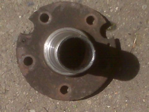 1995 Ford Bronco - Close-up of a rusted wheel hub, likely for an older vehicle, resting on gravel.