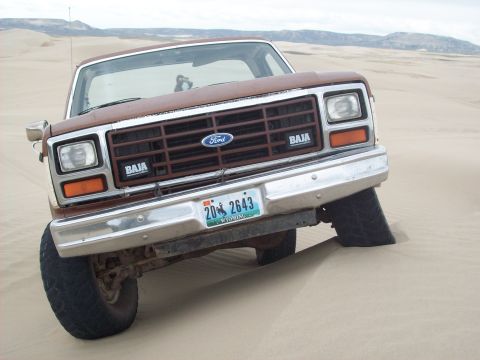 1985 Ford Bronco - This Ford Bronco, likely from the early 1980s, is partially submerged in sand dunes.