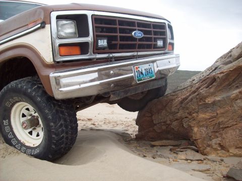 1985 Ford Bronco - This Ford Bronco is navigating a rocky obstacle on a sandy trail.