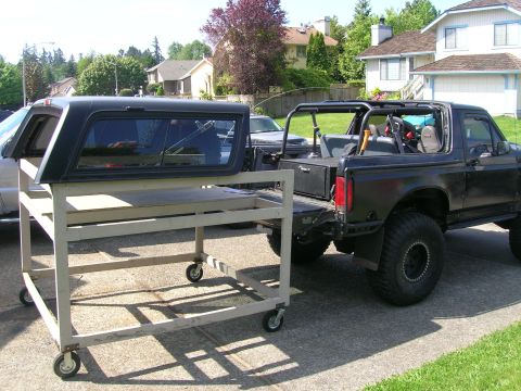 1996 Ford Bronco - 1996 Ford Bronco parked outside with a camper shell on a cart.