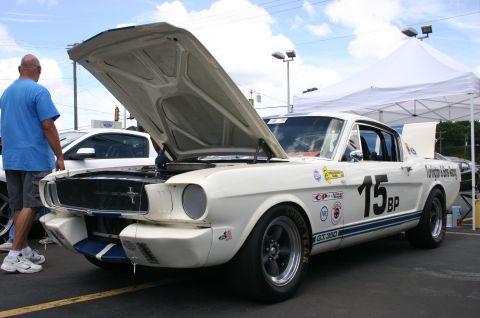 1968 Shelby GT500 - A white 1965 Shelby GT350 race car with its hood open is displayed at an outdoor event.