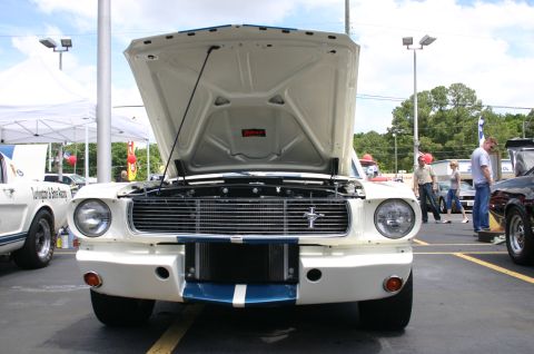 1968 Shelby GT500 - A white Ford Mustang is displayed with its hood open, revealing the engine bay. Another Mustang is parked nearby.