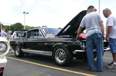 1968 Shelby GT500 - Two men examine the engine of a black 1968 Shelby GT500KR at a car show.
