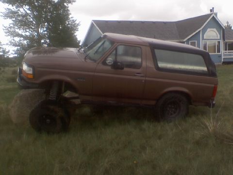 1993 Ford Bronco - This lifted 1993 Ford Bronco is parked in a grassy area with a house in the background.