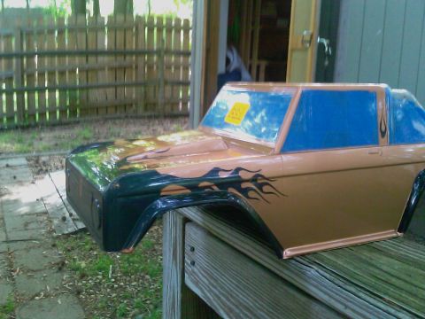 1996 Ford Bronco - A custom-painted Ford Bronco body shell with flame graphics sits outdoors on a wooden surface.