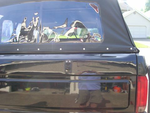 1996 Ford Bronco - Rear view of a black 1996 Ford Bronco, showing its soft top and a reflection in the tailgate.