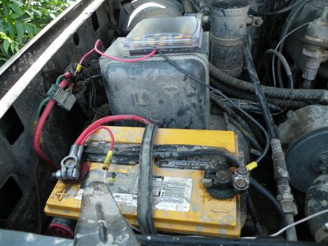 1986 Ford Bronco - Close-up view of a vehicle's engine bay, focusing on the battery and fuse box.