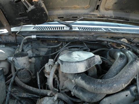 1986 Ford Bronco - The engine bay of a 1986 Ford Bronco reveals its internal components, coated in a layer of dust.