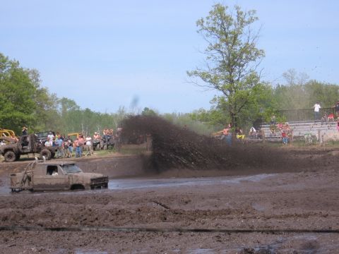 1999 Chevrolet Avalanche - A truck churns up a massive spray of mud while navigating a muddy track with onlookers in the background.