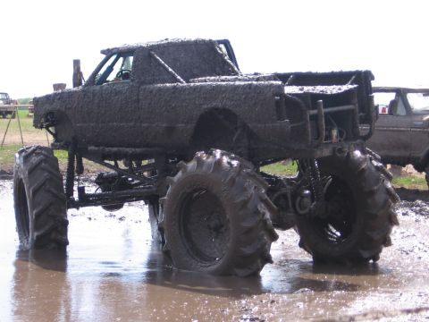1999 Chevrolet Avalanche - A heavily modified truck is covered in mud, with another vehicle visible in the background.