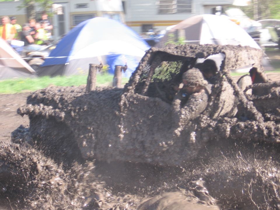 mud-covered off-road vehicle with occupants splashing through mud