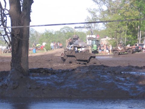 1999 Chevrolet Avalanche - Vehicles are stuck in deep mud during an outdoor event, with people watching from the sidelines.