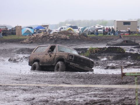 1999 Chevrolet Avalanche - A muddy SUV is stuck in a mud pit at an outdoor event.