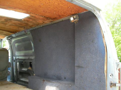 1978 Ford E250 - The interior of a van, carpeted walls and a wooden ceiling with a skylight.