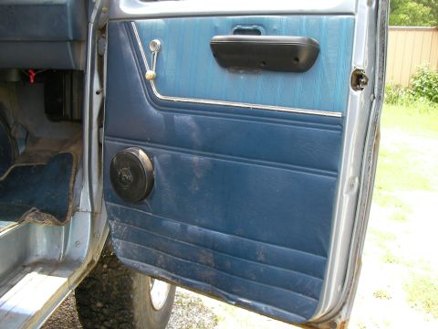1978 Ford E250 - Interior door panel features blue vinyl and a black speaker, with a chrome window crank visible.
