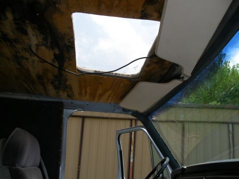 1978 Ford E250 - The interior of a van shows a large skylight and a sun visor, with a view of the outside through the windshield.