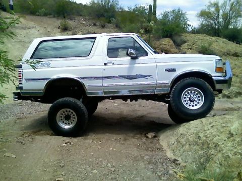 1996 Ford Bronco - White 1996 Ford Bronco navigates rocky terrain off-road.
