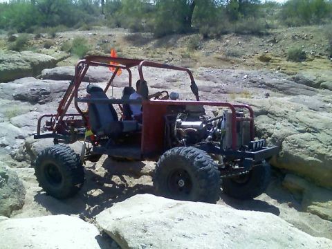 1996 Ford Bronco - A custom-built off-road buggy navigates a rocky trail under a bright sky.